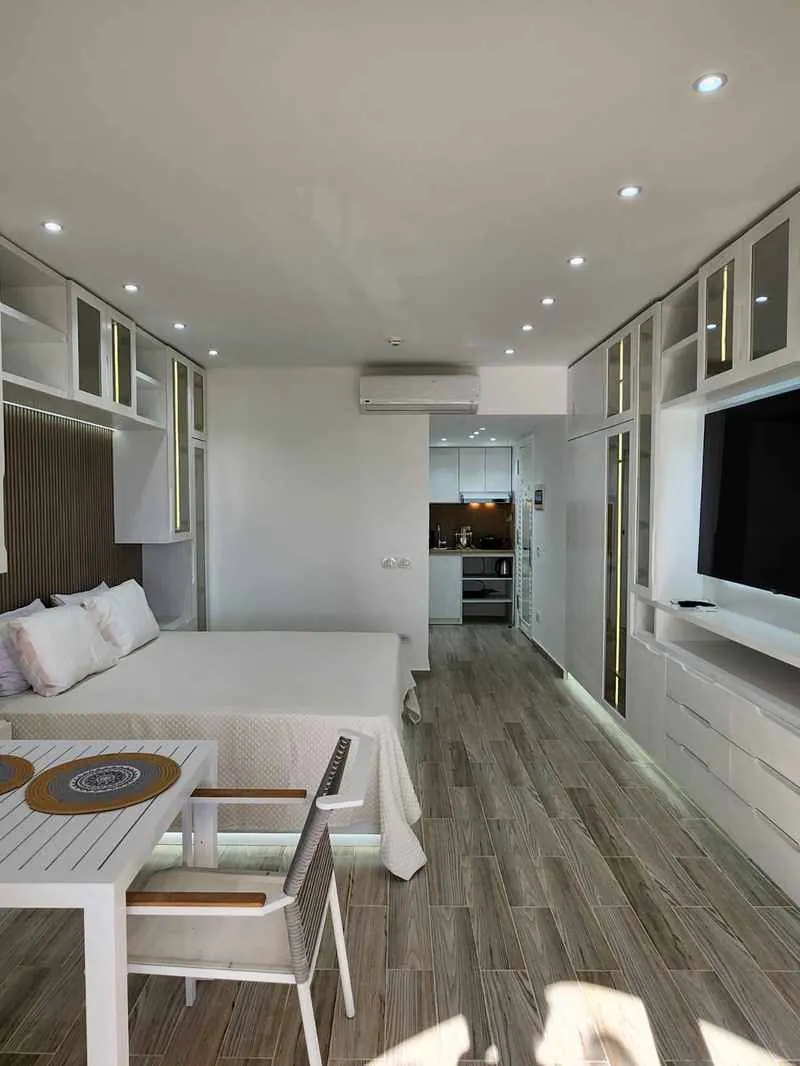 Ambiente con pavimento effetto legno, letto e zona pranzo
