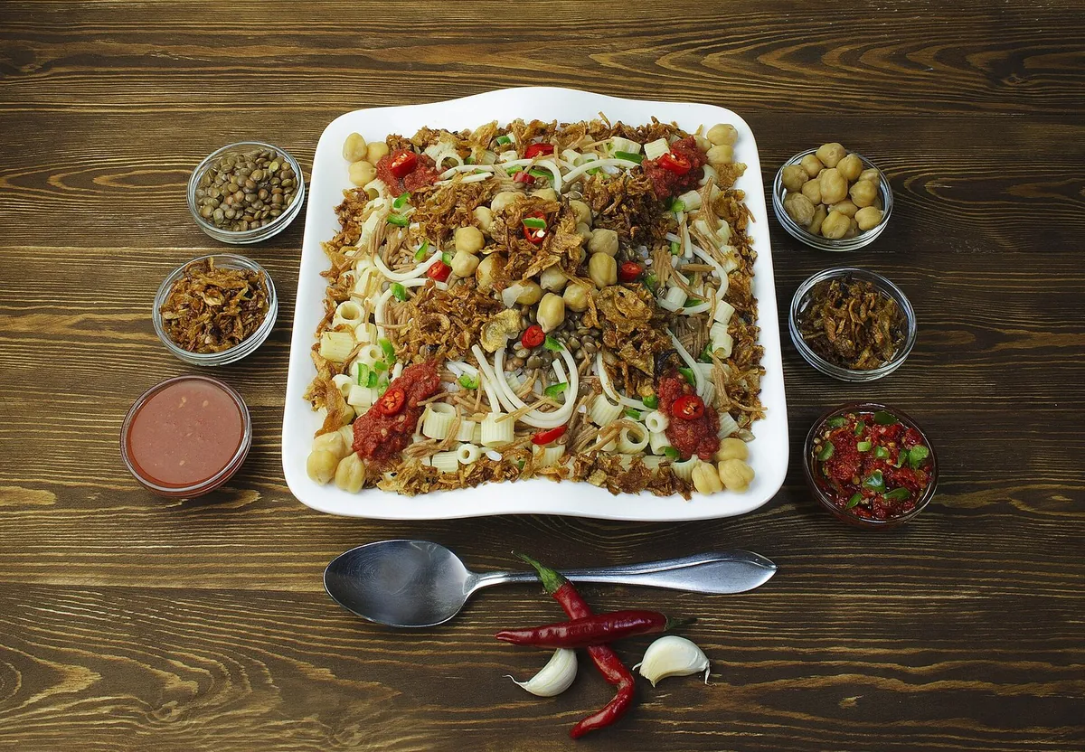 Un piatto di koshari, il piatto nazionale egiziano, con i condimenti in ciotoline attorno