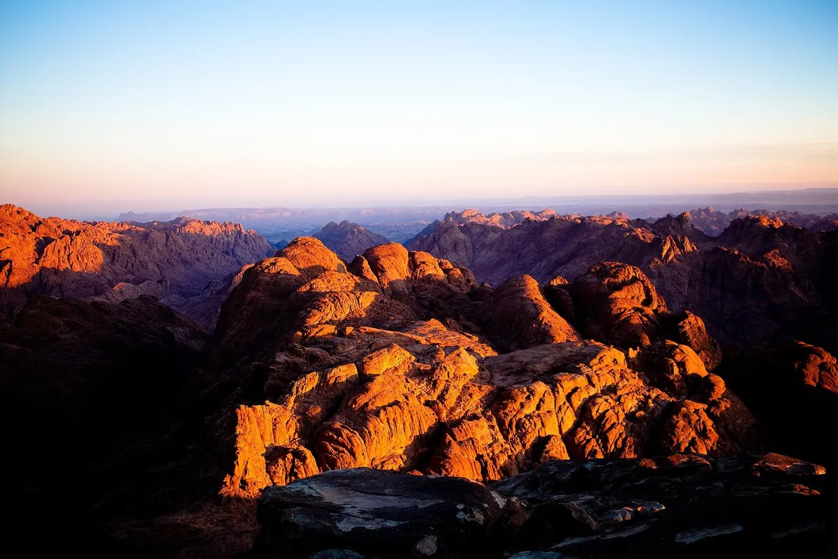 Le cime di granito del Sinai accese di arancio dal sole dell'alba, viste dal Monte Sinai